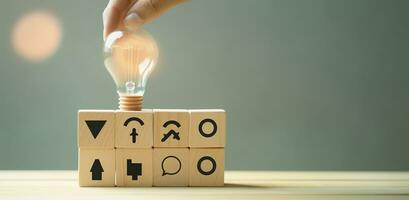 AI generated Creative idea, solution and innovation concept. Idea generation for business development. Wooden cube blocks with light bulb and cycle icons on clean background and copy space. photo