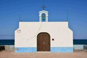 a small white chapel with blue trim and a cross on top photo