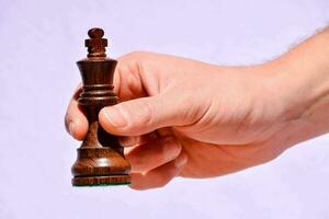 a hand holding a wooden chess piece photo