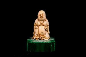 a small statue of a buddha sitting on a green base photo