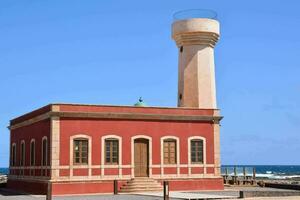 a lighthouse on the beach in front of a building photo