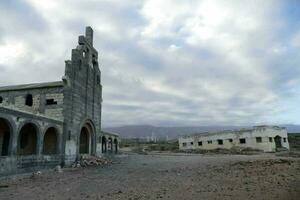 an abandoned church sits in the middle of a desert photo