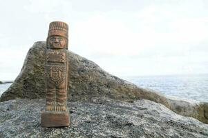 a wooden figure sitting on top of a rock photo