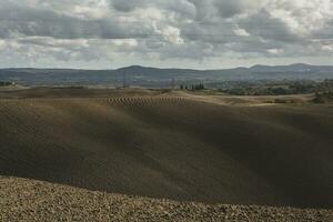 cosechado campos y prados paisaje en toscana, Italia. ondulado país paisaje a otoño puesta de sol. cultivable tierra Listo para el agrícola estación. foto