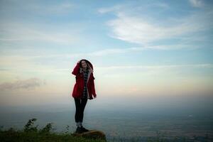 Portrait of a beautiful young woman in red coat on the background of blue sky photo