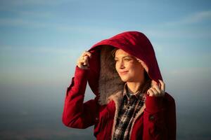 Portrait of a beautiful young woman in red coat on the background of blue sky photo