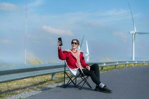 On the background of windmills, A young woman in a red jacket is enjoying her winter vacation. photo