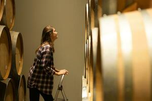 Portrait of a young woman surrounded by wine barrels In her winery photo