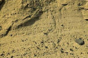 a rock is sitting on the ground next to a sand dune photo