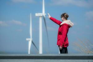 On the background of windmills, A young woman in a red jacket is enjoying her winter vacation. photo