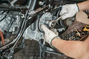 Mechanic using wrench and socket to Remove auto Transmission system or Rear Clutch Pulley of scooter Motorcycles,working in garage maintenance, repair motorcycle concept .selective focus photo