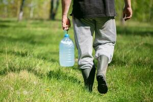 A man carries a jar filled with birch sap. photo