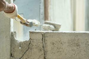 Hand of worker using hammer smashing and demolish on brick wall at construction site photo