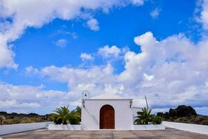 a white church with a blue sky and clouds photo