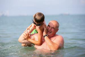 contento abuelo y nieto son jugando en el mar agua.padre y hijo son descansando en el mar. foto