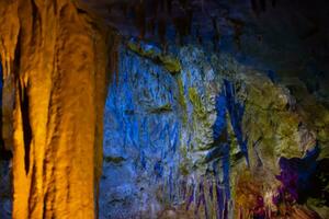 Karst cave, amazing view of stalactites and stalagnites in colorful bright light, beautiful natural landmark in touristic place. photo