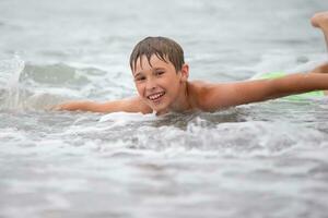 el cara de un contento chico quien nada en el mar. foto