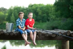 Children on a fishing trip. The boys are fishing with a fishing rod in the lake. photo