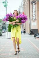 hermosa mayor mujer con un enorme ramo de flores de flores en el ciudad. foto