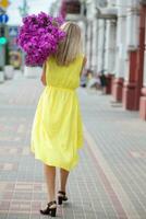 un mujer es caminando abajo el calle con un enorme ramo de flores de flores detrás su. foto
