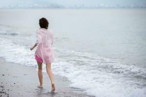 A middle-aged woman runs along the seashore. photo