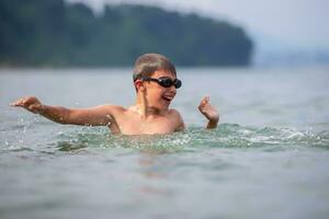 A boy in swimming goggles swims in the sea. photo