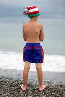 Boy in a Christmas hat on the seashore. Meeting Christmas in the southern countries. photo