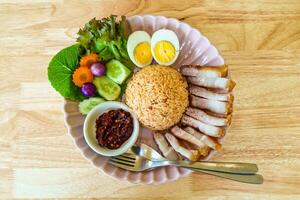 crujiente Cerdo frito arroz con chile pegar, hervido huevo y hierba, vegetal de tailandés comida foto