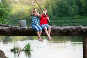 Happy friends boys caught a fish with a fishing rod. photo