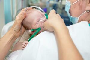 bebé con un oxígeno máscara en el neonatal unidad.bebe vestir oxígeno máscara foto