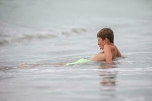 Happy boy playing with the sea wave, enjoying the sea. The child bathes, sunbathes and rests. Summer holidays. photo