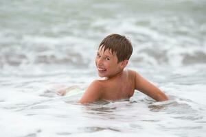 A happy boy is lying by the sea, smiling and looking at the camera. photo