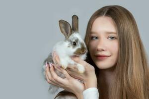 Girl holding a rabbit close-up on a gray background. photo