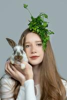 A rural girl with a bunch of parsley on her head is holding a pockmarked rabbit. photo