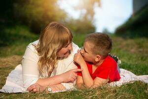 Happy mom and son on a summer picnic communicate, spend time together, lie on the grass. Mothers Day. photo