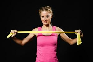 Beautiful young woman is exercising with rubber band. photo