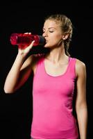 Beautiful blonde woman is drinking water after exercise. photo