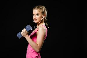 Woman is exercising with dumbbells and listening music photo