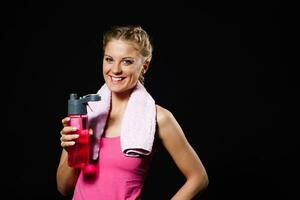 Beautiful blonde woman is drinking water after exercise. photo