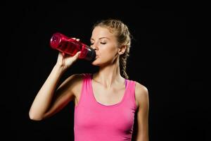 Beautiful blonde woman is drinking water after exercise. photo