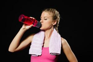 hermosa rubia mujer es Bebiendo agua después ejercicio. foto