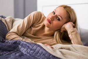 Sad woman in pajamas lying on a bed in bedroom. photo