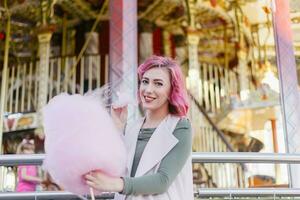 pink hair girl short haircut posing in amusement park on carousel background. photo