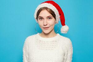 bonito rubio vistiendo Navidad sombrero en ligero azul antecedentes foto