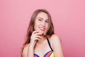 Adorable brunette in bikini posing on pink background photo