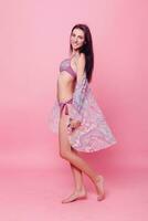 Adorable brunette in bikini posing on pink background photo