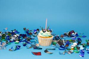 birthday cupcake with three burning candles over blue background photo