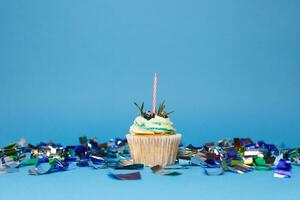 birthday cupcake with three burning candles over blue background photo