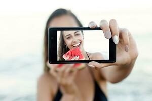 Summer vacation - young girl eating fresh watermelon on sandy beach photo