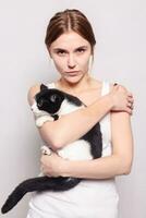 Beautiful smiling woman with a kitten in her arms, studio picture, close-up photo